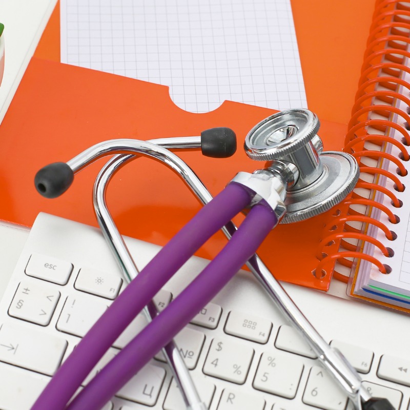 Keyboard, orange folder and purple stethoscope